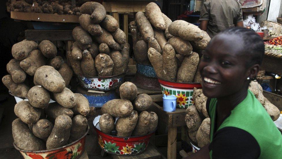 A young woman at a market stall which sells yams