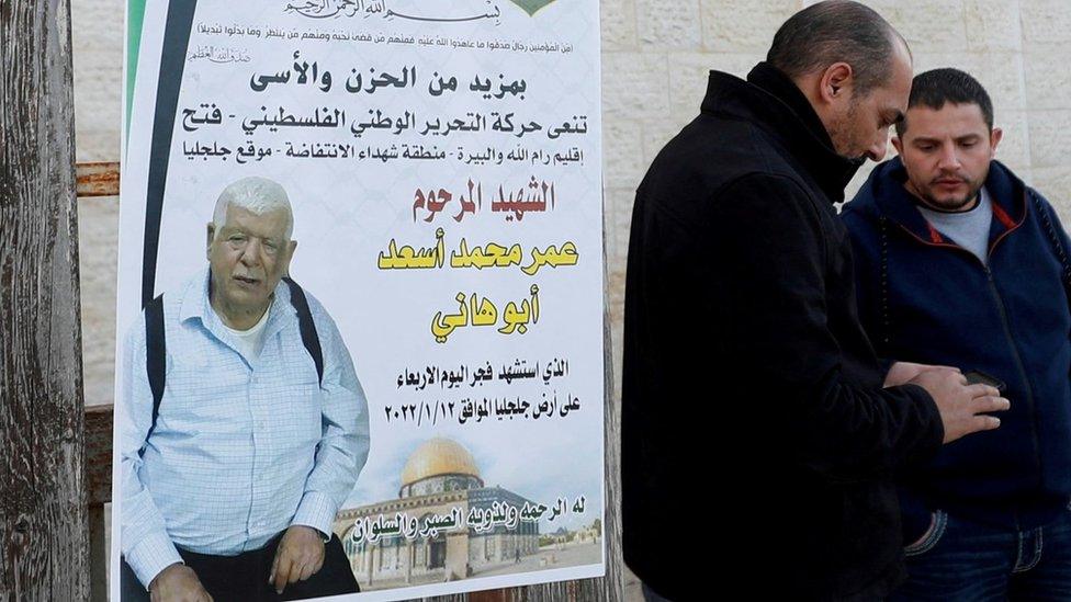 Men stand next to a poster of Palestinian Omar Asad, 80, in Jiljilya village, in the Israeli-occupied West Bank. Photo: January 2022