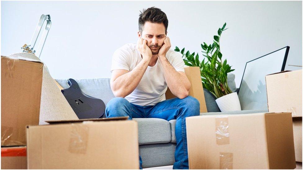 Man sits with boxes all around him