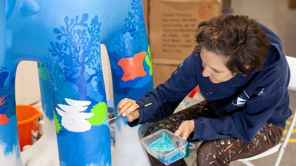 Artist painting a sculpture