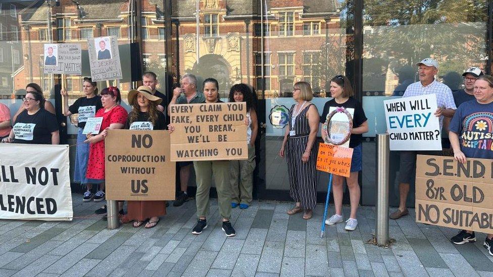 A line of parents outside the council offices with placards protesting about SEND provision