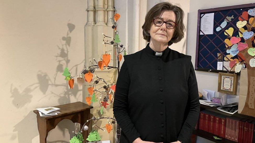 Reverend Canon Poppy Hughes, standing inside St Mary's Church in Tetbury wearing her dog collar