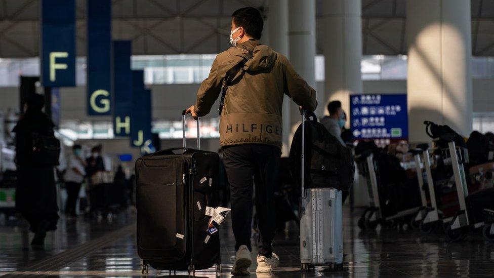 A man wheels suitcases through an airport