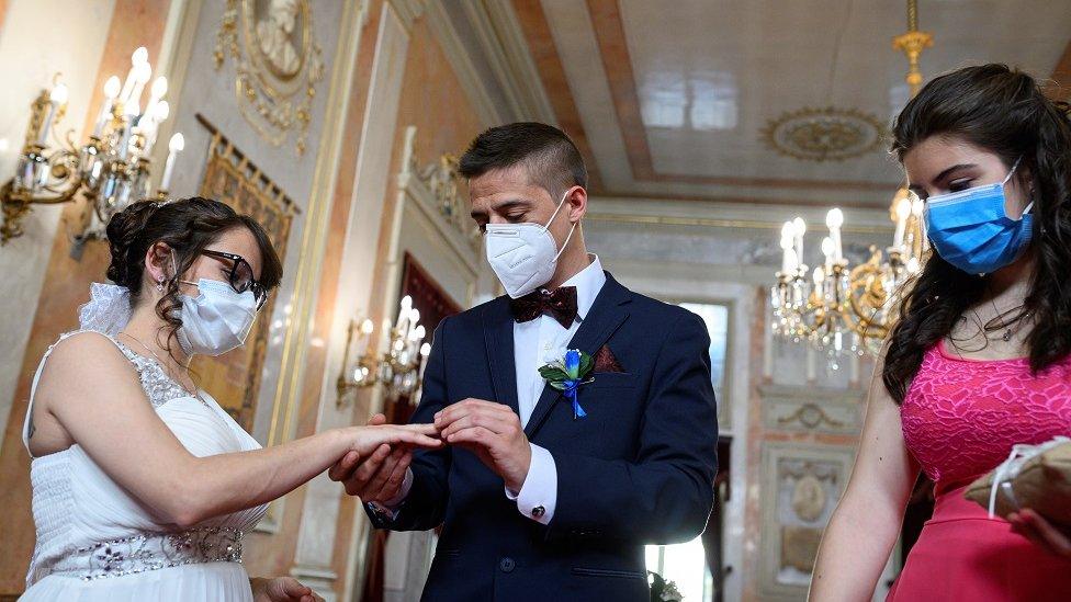 Groom Iker (R) places a wedding ring on the hand of bride Aranzazu (L) as the bridesmaid (R) looks on during their civil wedding at the town hall of Alcala de Henares, Madrid, Spain, 06 June 2020. The nuptial ceremony was one of the first held there since the the state of emergency was implemented in March throughout Spain due to the pandemic COVID-19 disease caused by the SARS-CoV-2 coronavirus.