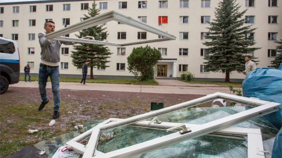 Refugee piles up damaged windows in Suhl (20 Aug)