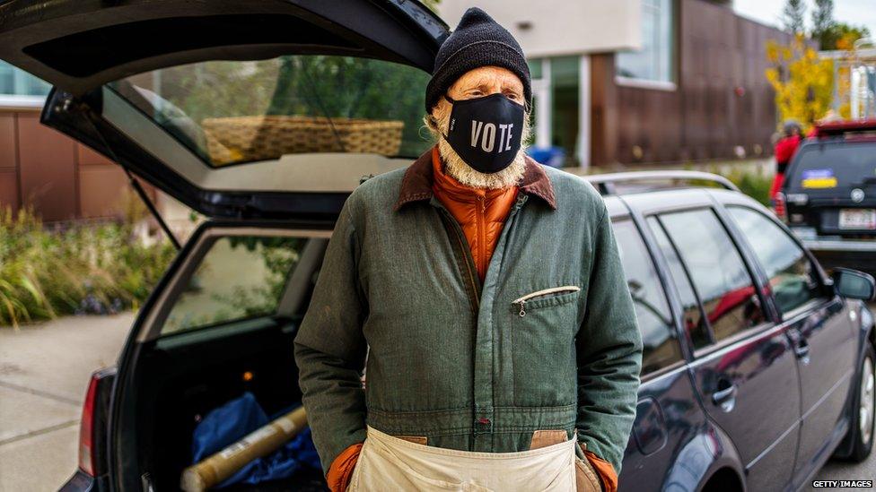 Apple vendor Rikardo Jahnke wears a facemask reading "vote" at the farmers market in Viroqua, Wisconsin