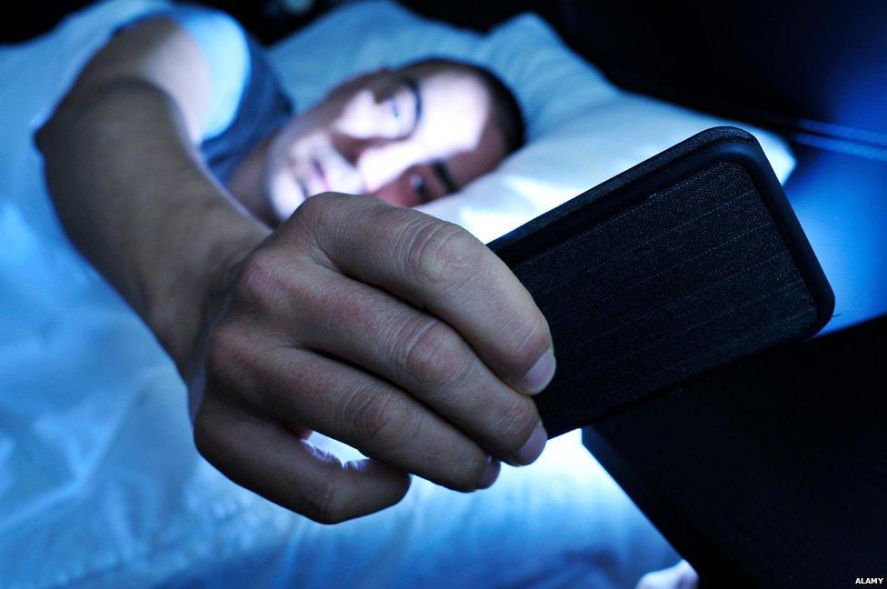 Man holding phone in bed