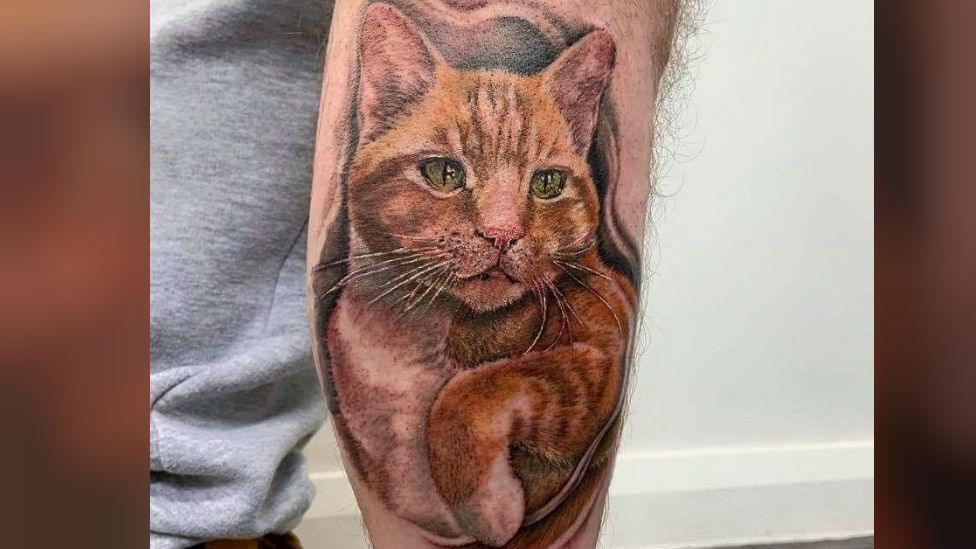 Tattoo of cat on man's leg