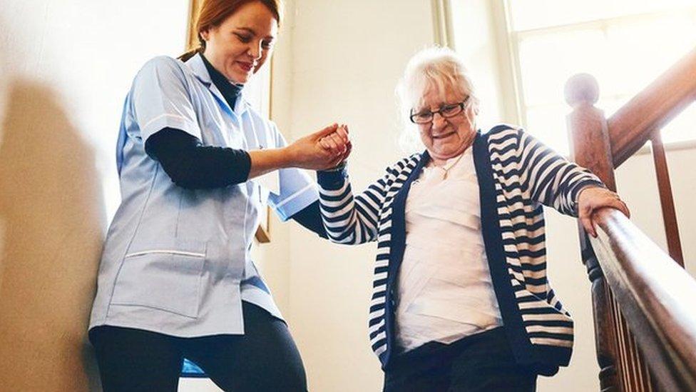 A care worker helping a woman downstairs