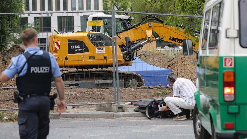 Image shows a blue tent covering the bomb and a police officer in the foreground.