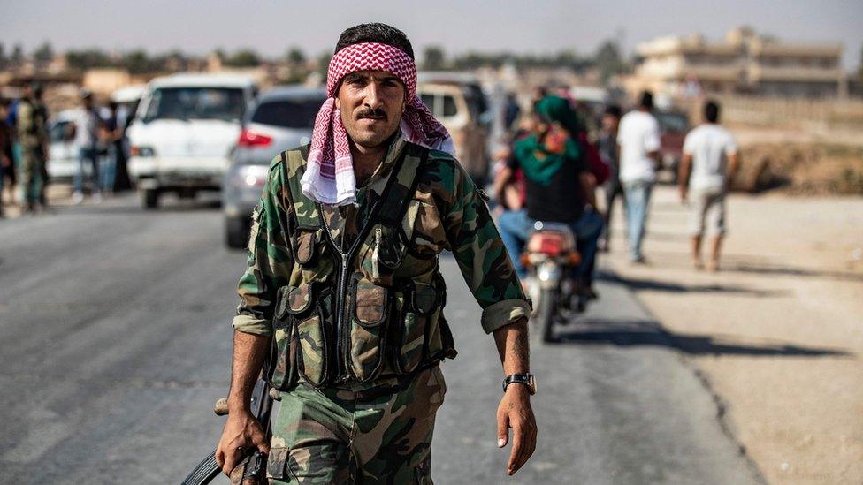 A Syrian regime soldier patrols a street