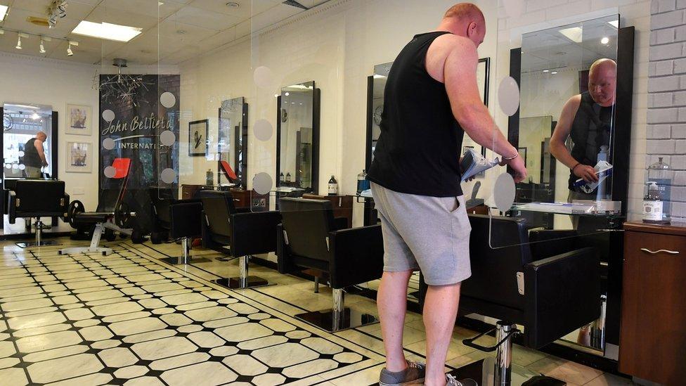 Hairdresser John Belfield prepares his hair salon, adapted with perspex screens in between customers' seats, in Newcastle-under-Lyme