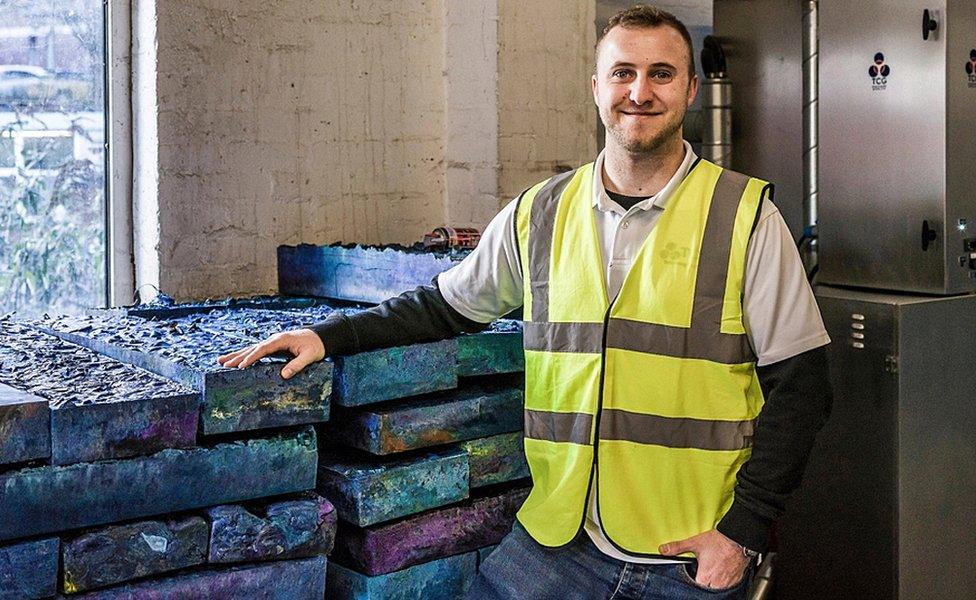 A Thermal Compaction Group worker standing in front of its blocks of recycled plastic