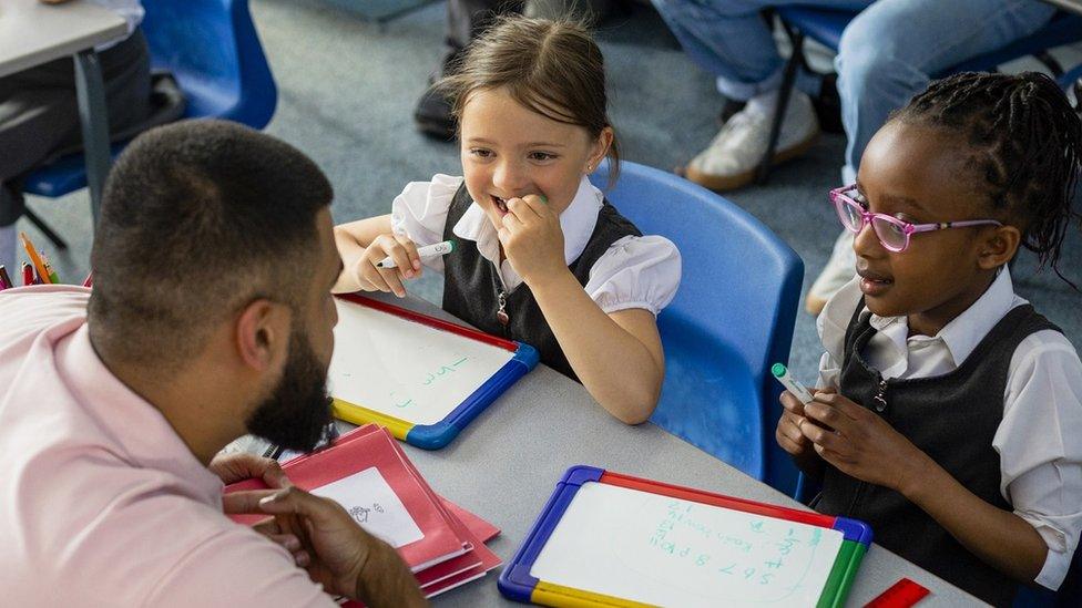 Stock image of primary school teacher and children