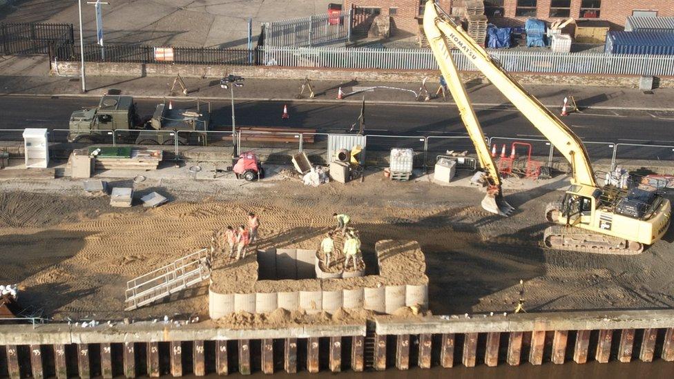 A crane lifting sandbags into position