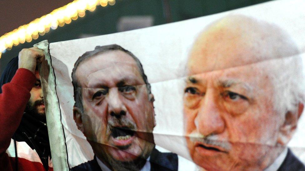 A Turkish protester holds up a banner with pictures of Recep Tayyip Erdogan and exiled Turkish cleric Fethullah Gulen during an anti-government demonstration