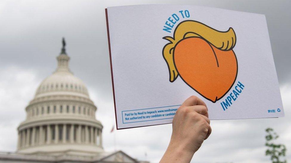 An impeachment sign is held up near the US Capitol.