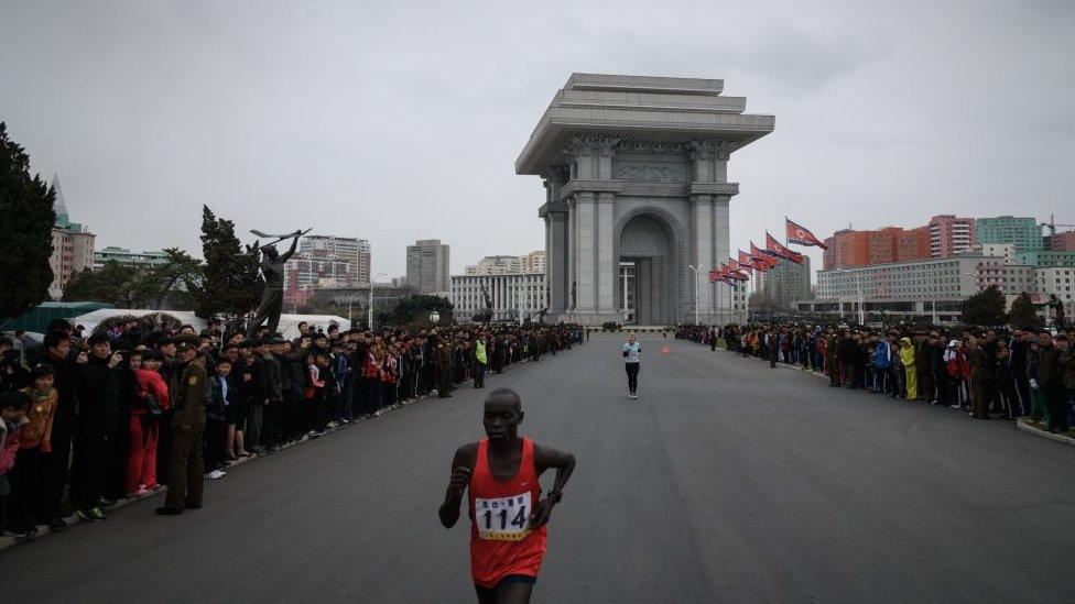 Competitors run past Pyongyang's Arch of Triumph near the end of the race