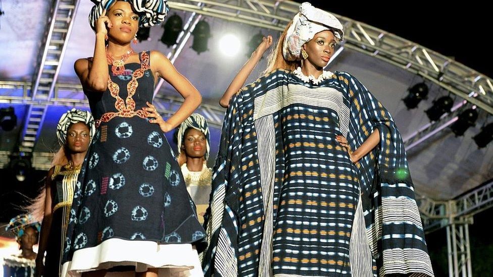 Models present creations by Ivorian designer Momotche outside the palais de la culture in Abidjan on March 11, 2016