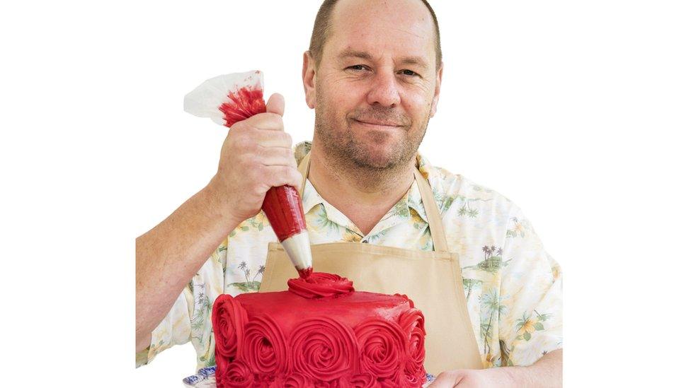 Jon icing a red cake with roses