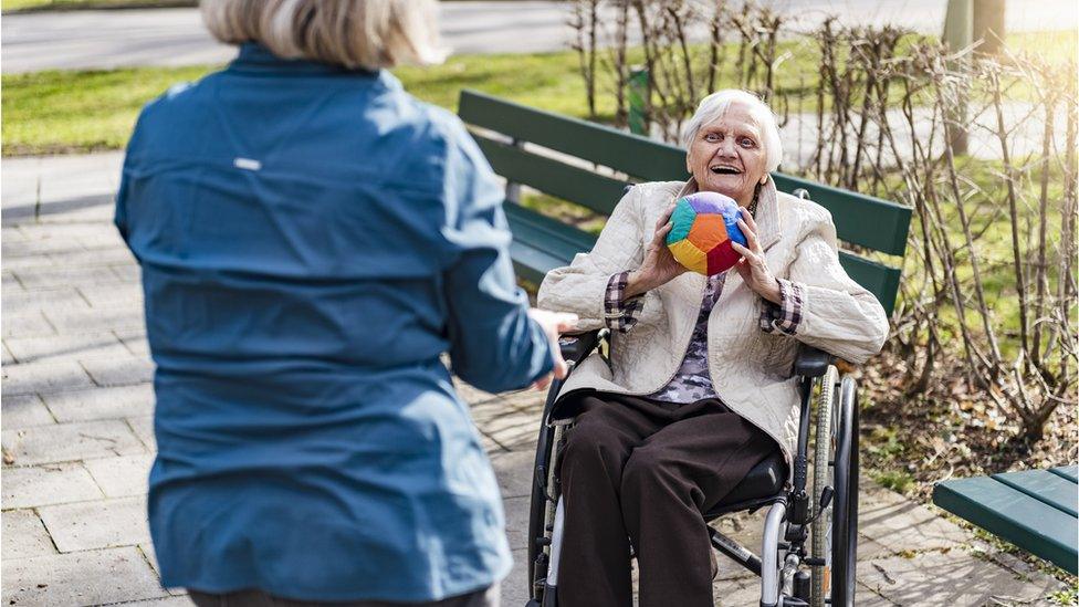 Care home resident throwing ball outdoors