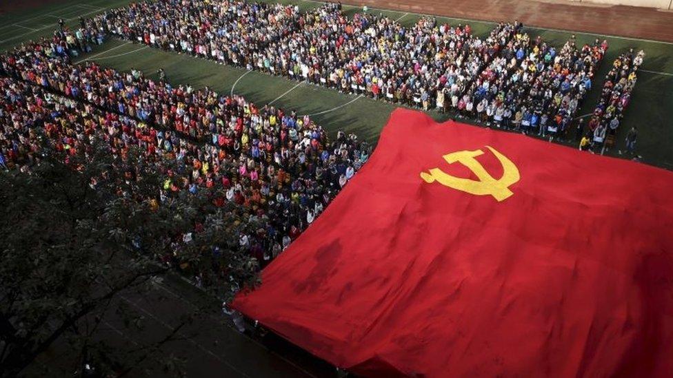 Chinese students pass above their heads a 90-meter-wide flag of the Chinese Communist Party at the semester commencement ceremony of a middle school in south-western China's Chongqing Municipality (24 February 2016)