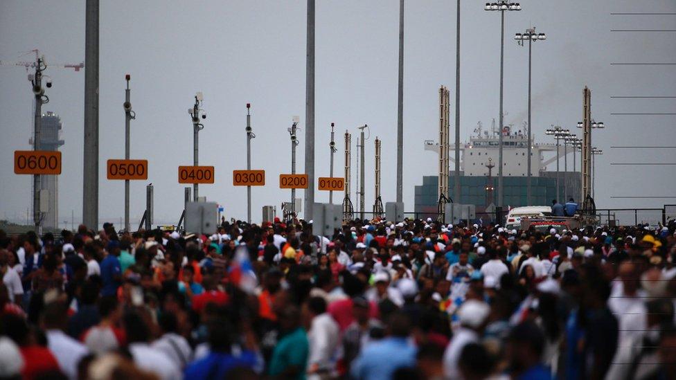 Spectators watch as the ship sails along the canal