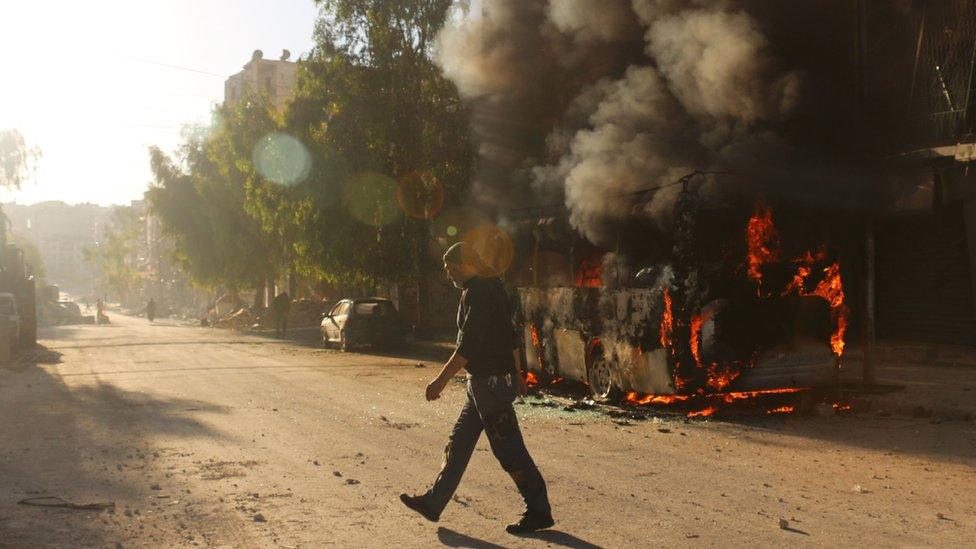 A Syrian man walks past a bus set ablaze following a reported air strike in the rebel-held Salaheddin district of Aleppo, 25 September 2016