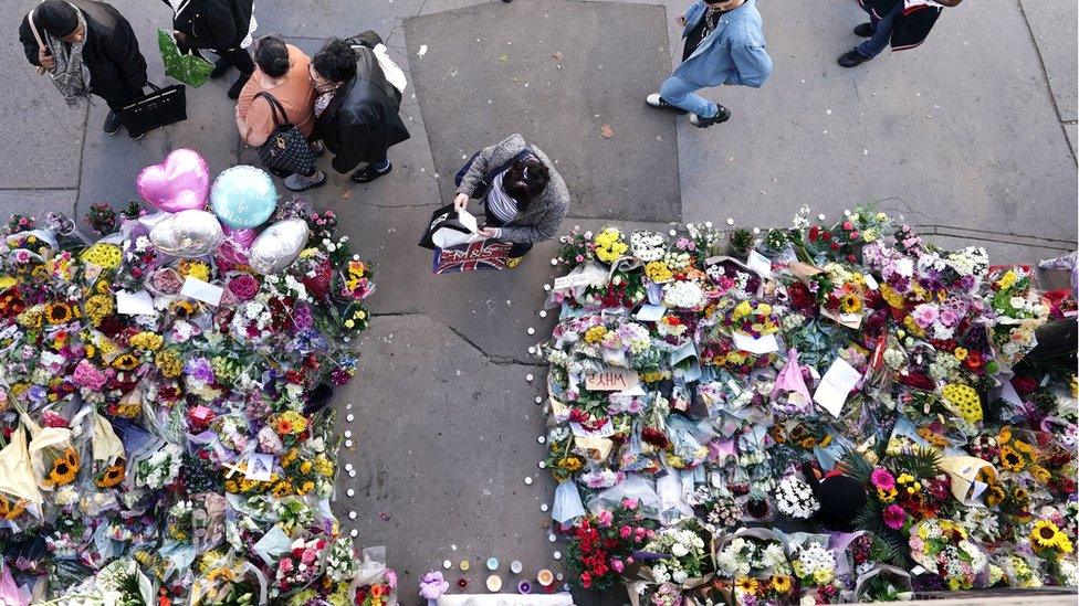 People laying flowers near the scene where Elianne Andam was stabbed