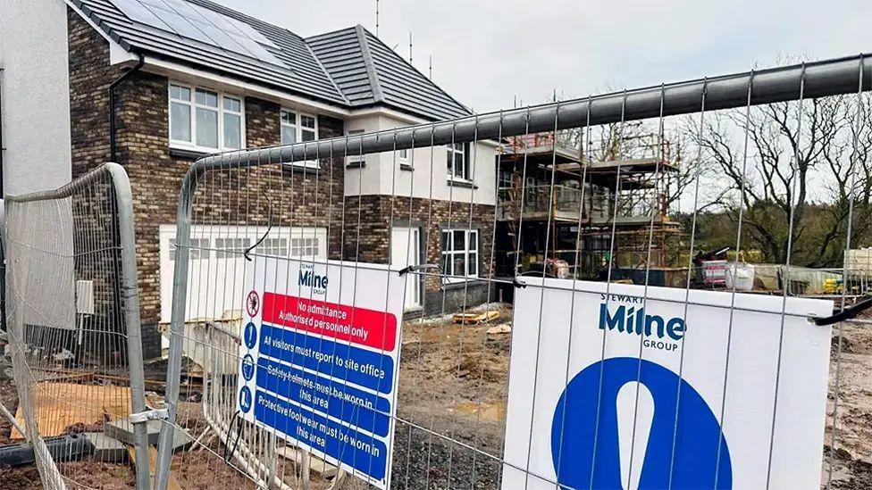 Construction site with a Stewart Milne sign and housebuilding work.