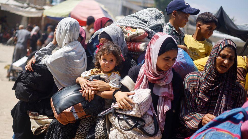 Palestinians ride on a vehicle loaded with belongings as they leave Khan Younis