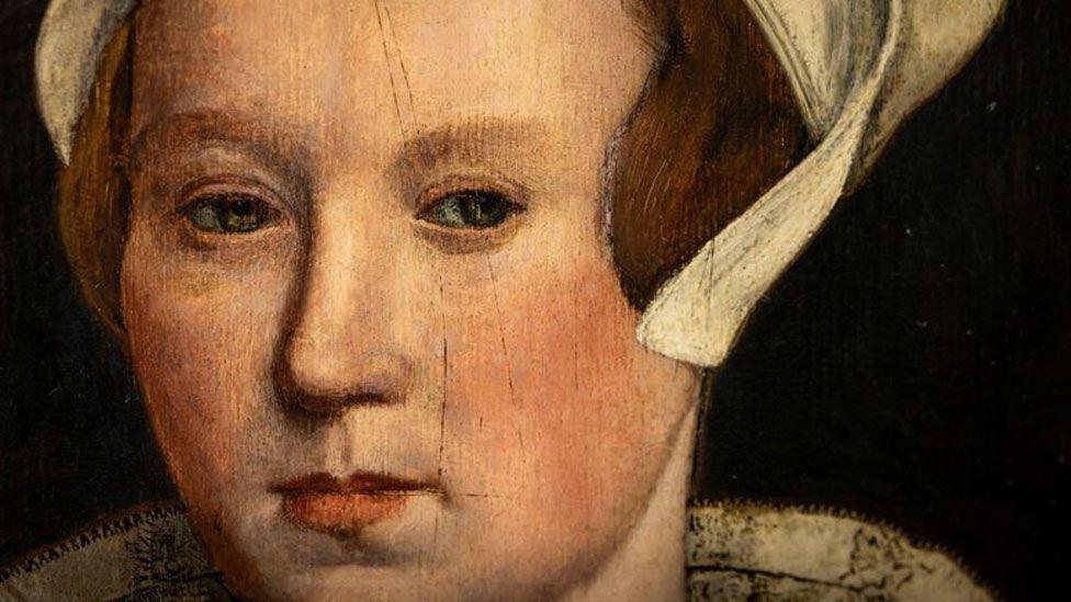 A close-up of a portrait of a Tudor woman believed to be Lady Jane Grey. She has reddish hair under a white linen cap. She is looking left.