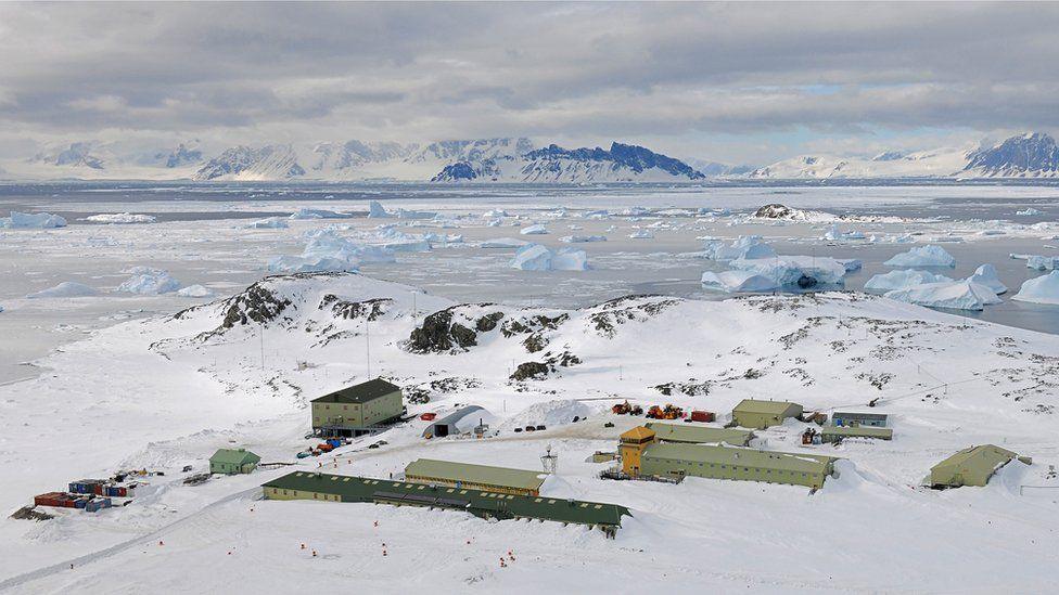 Rothera is the UK's biggest Antarctic base and is a collection of green buildings in the snowy landscape. The icy sea is beyond the land and in the background are snow-covered mountains