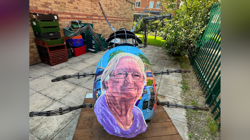 A large tansy beetle sculpture with a colourful portrait of Rosie Wall painted on its back