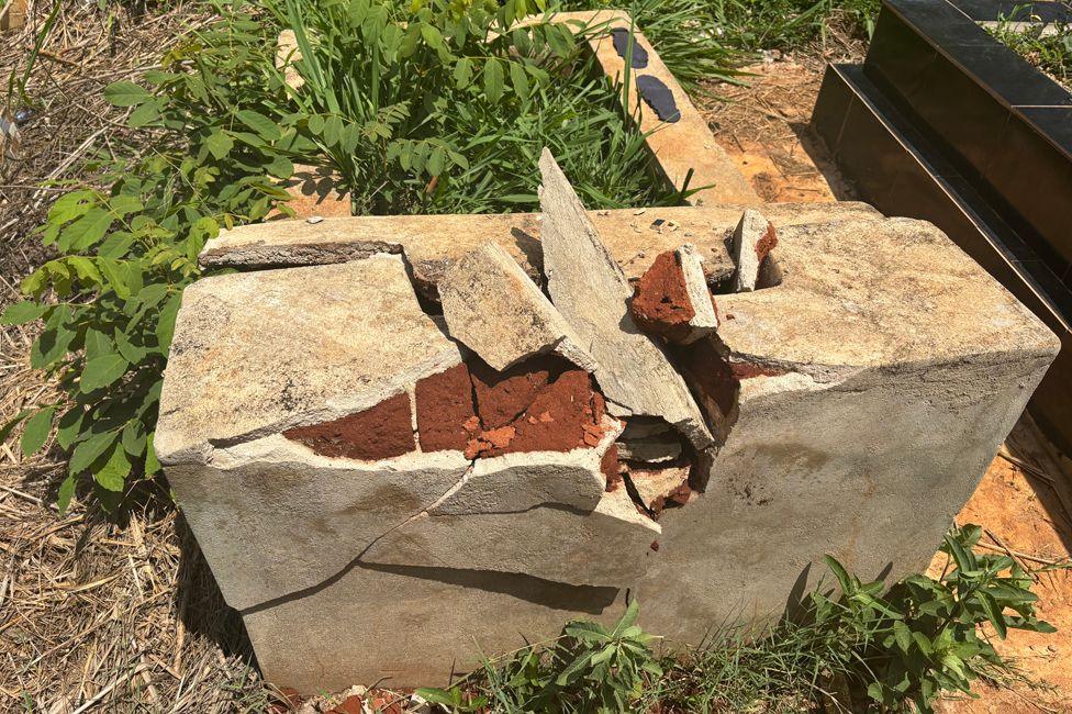 A grave in the Kola Municipal Cemetery with a broken concrete headstone where a cross was once placed. 