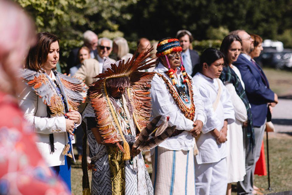 People wearing traditional clothing listen to a speaker (out of shot) at the Harmony Summit