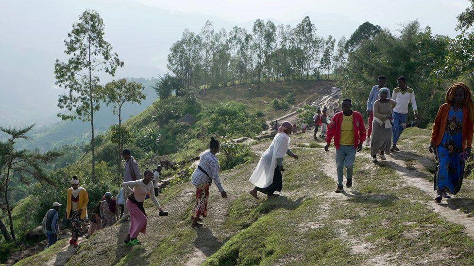 People walking up a steep path in Gofa at the scene of two landslides