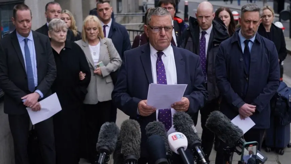 Gary Furlong standing with other members of the victims' families outside the Old Bailey in front of microphones, reading a statement following the conclusion of the men's inquests in April 2024.