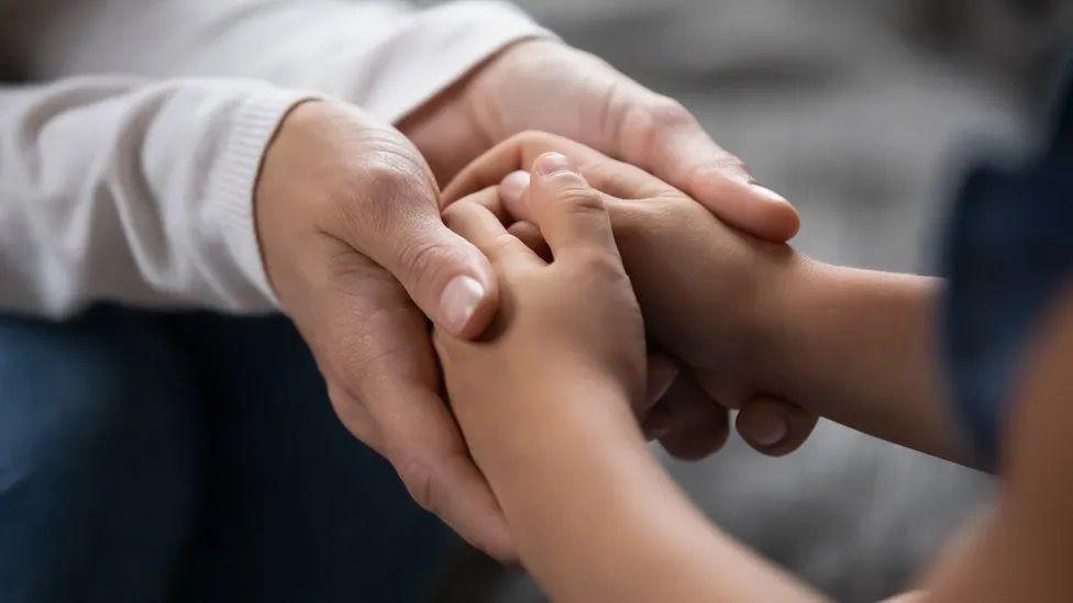 An adult holding a childs hand