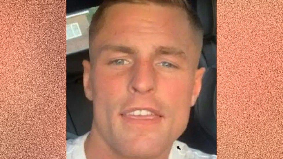 A selfie of Jamie Lucas smiling at the camera. He has a tanned complexion and short blonde hair combed in a side shed. He appears to be sitting in a car.