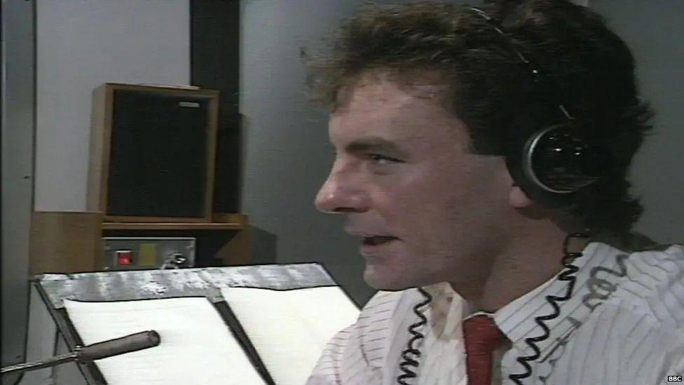 Old photograph of Mike Nesbitt sitting in a radio studio talking into a microphone. He is wearing a shirt and tie and headphones.