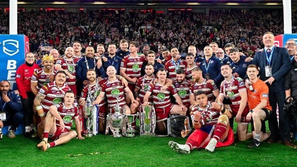 Wigan Warriors pose with the four trophies they won in 2024