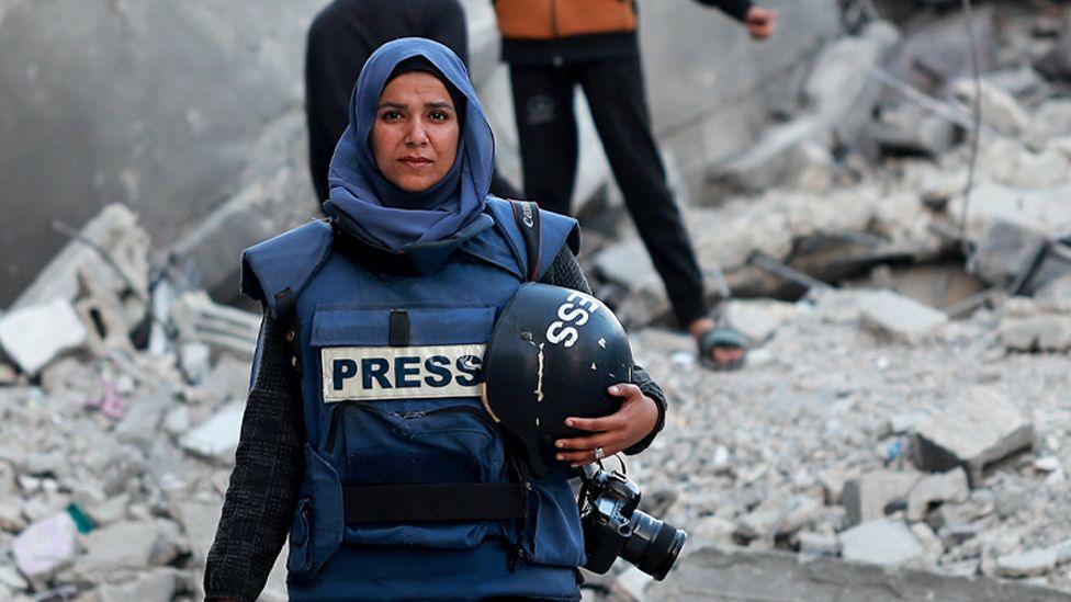 Photojournalist Doaa Albaz is photographed in the ruins of Rafah City, rubble all around her.