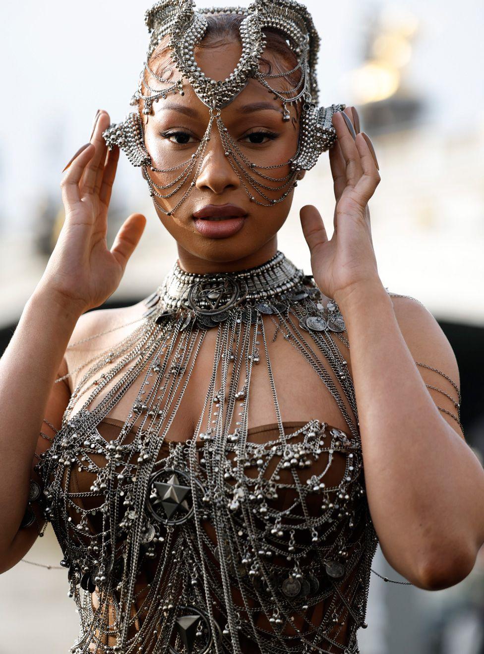 Megan Thee Stallion wearing an elaborate outfit with lots of metallic wires coming out of a metal neckpiece, and a headpiece made from shaped wires 