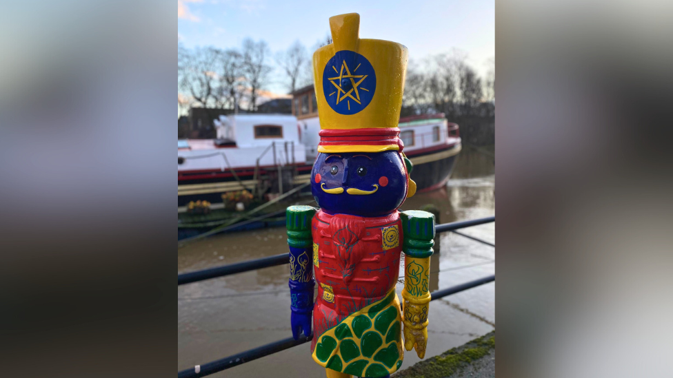 A green, blue, red and yellow nutcracker statue stood on the bank of the River Ouse