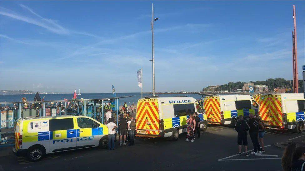 Five police vans parked by the sea