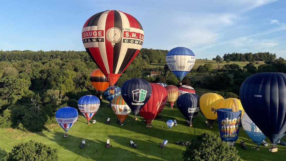 Around 18 hot-air balloons rising from the ground on Ashton Court Estate