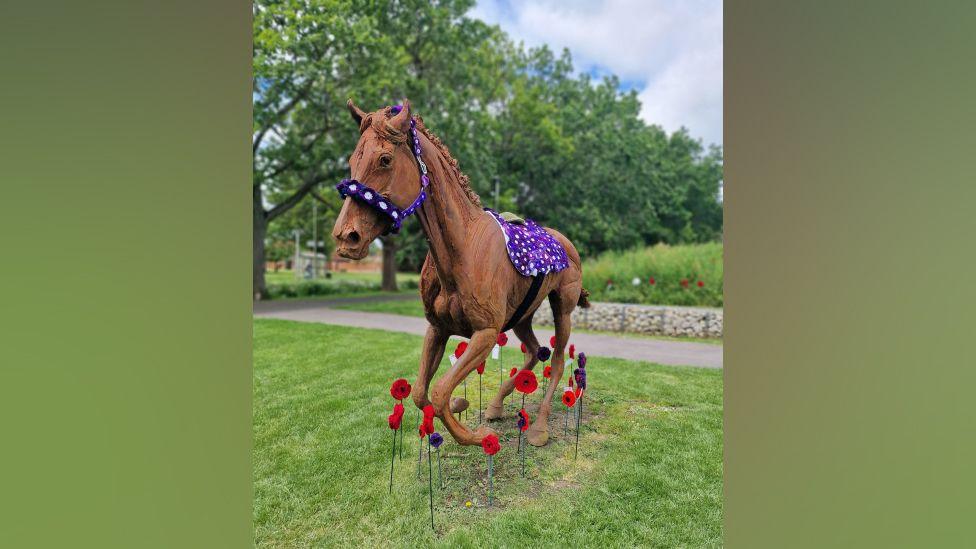 One of the horse statues with the purple poppies with white hearts prepared by the group