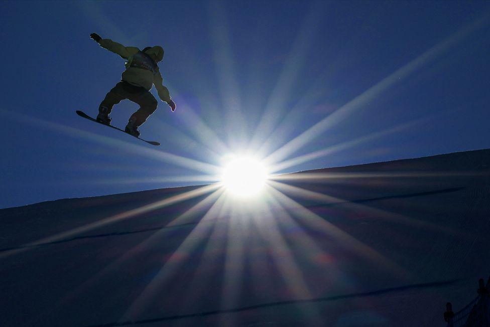 Dane Menzies of New Zealand takes to the air in the men's snowboard slopestyle qualifiers during the Toyota US Grand Prix at Buttermilk Ski Resort in Aspen, Colorado, with bright sun in the background