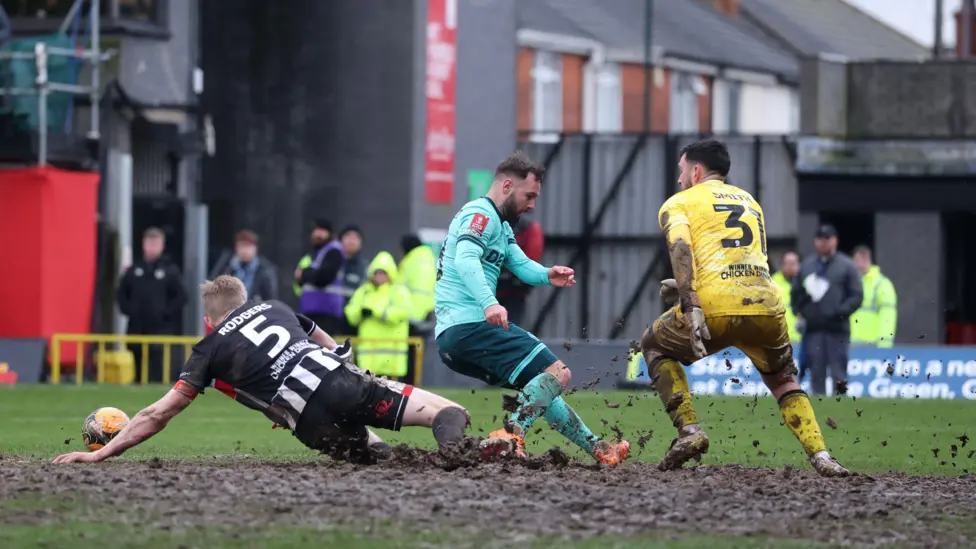Wolves' Adam Armstrong attempts to meet a cross under pressure from Grimsby's Jackson Smith and Harvey Rodgers